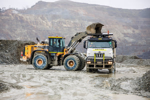 Mining digger tipping into truck in PNG