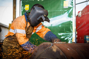 Heavy machinery maintenance by a worker in hi vis